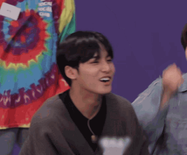 a man wearing a tie dye shirt looks at the camera