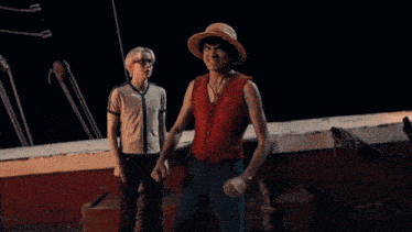 a man wearing a straw hat and a red vest is holding a knife