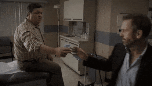 a man in a suit shakes hands with another man in a chair
