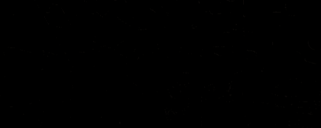a man is sitting on a couch with his legs crossed in a dark room