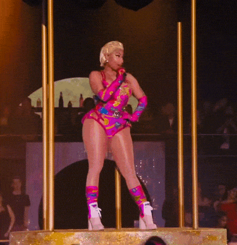 a woman is singing into a microphone while standing on a stage in front of a crowd