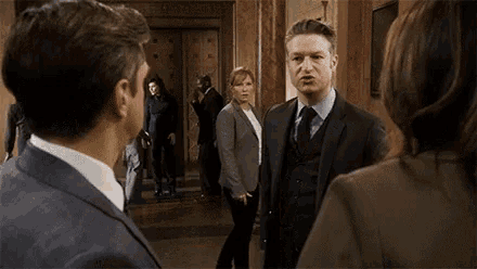 a man in a suit is making a funny face while talking to two women