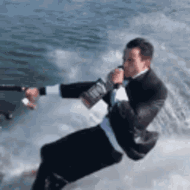 a man in a suit is water skiing in the water while drinking from a bottle .