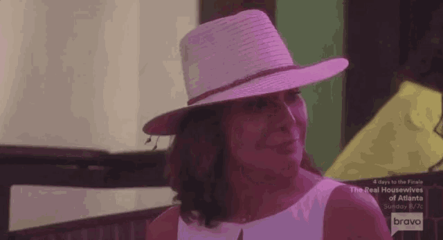 a woman wearing a pink hat and a white dress is sitting on a bench .