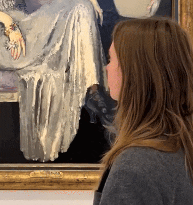 a woman is looking at a painting with a gold frame that says mcfarlane