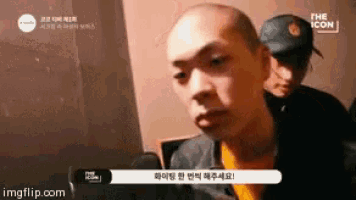 a man with a shaved head is talking to another man .