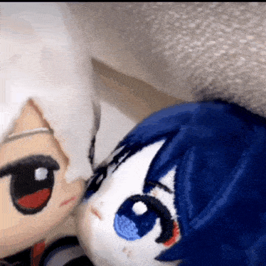two stuffed dolls are sitting next to each other on a bed