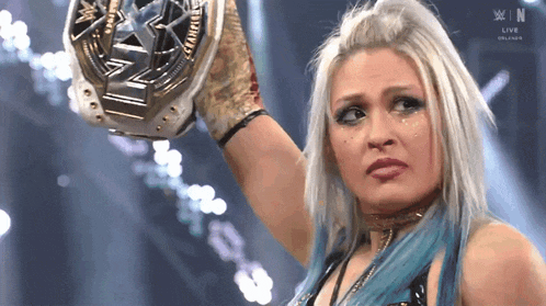 a female wrestler is holding a wrestling championship belt