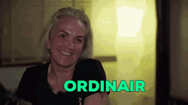 a woman is smiling with the word ordinair behind her