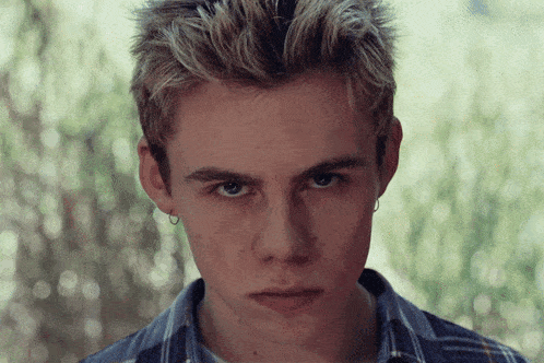 a close up of a young man 's face with a serious look on his face