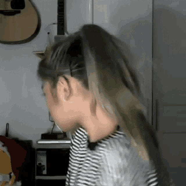 a woman is wearing a ponytail and a striped shirt .