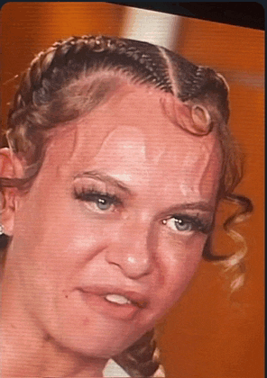 a close up of a woman 's face with sweat coming out of her hair