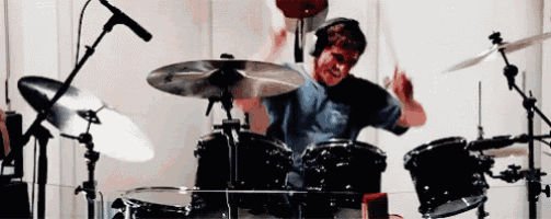 a man in a blue shirt is playing drums in a room .