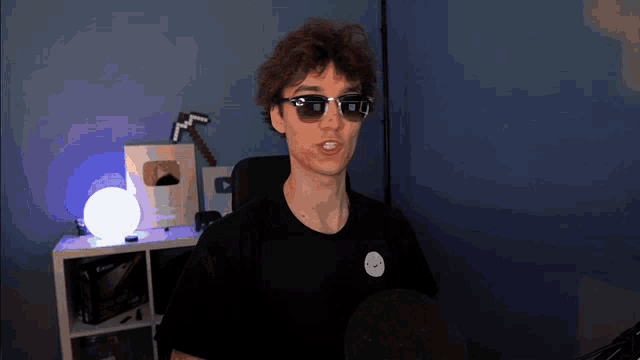 a man wearing sunglasses is sitting in front of a microphone in a room .