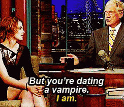 a woman sits on a couch talking to a man in a suit