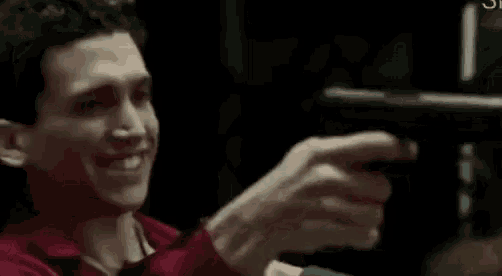 a man is holding a gun in his hand and smiling .