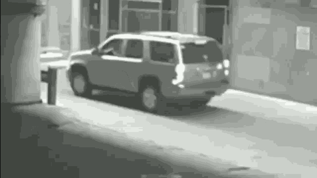 a black and white photo of a suv parked on the side of the road in front of a building .