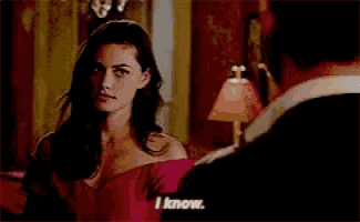 a woman in a red dress is talking to a man in a dark room .