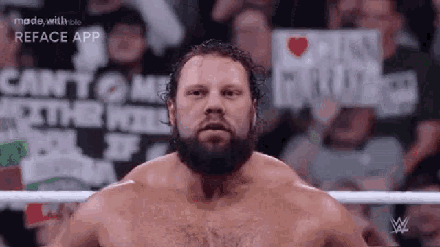 a man with a beard is in a wrestling ring with a crowd behind him .