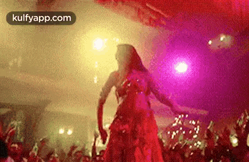 a woman in a red dress is dancing in front of a crowd at a party .