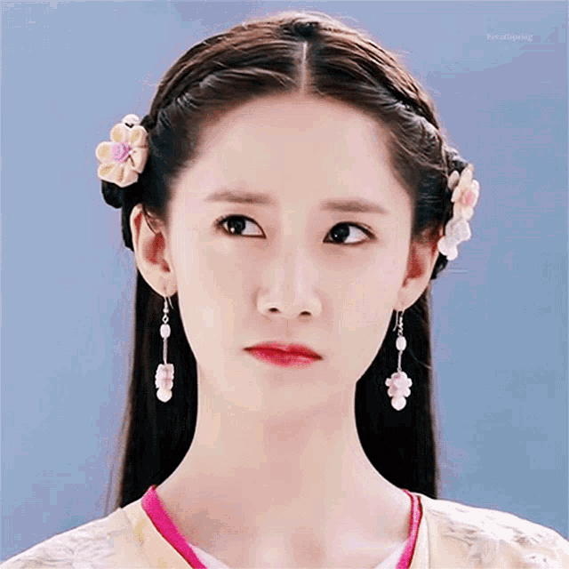 a close up of a woman 's face wearing earrings and a flower in her hair