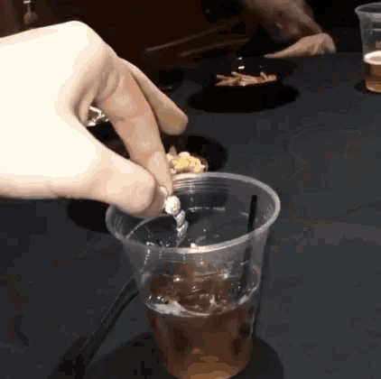 a person pouring something into a plastic cup