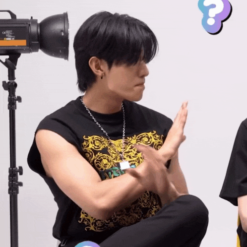 a man sitting in front of a camera with a question mark