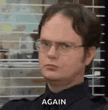 dwight schrute from the office wearing glasses and a black shirt is making a funny face .