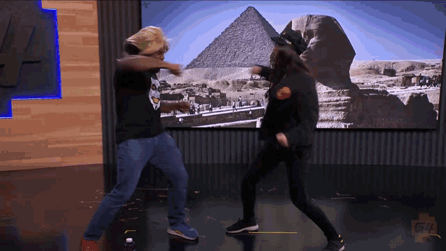 a man and a woman are dancing in front of a screen that says gfl