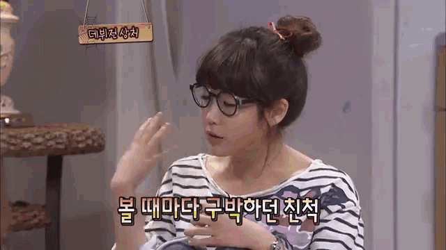 a woman wearing glasses and a striped shirt has a sign above her that says ' korean ' on it