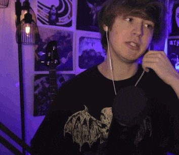 a man wearing ear buds and a black shirt with a bat on it