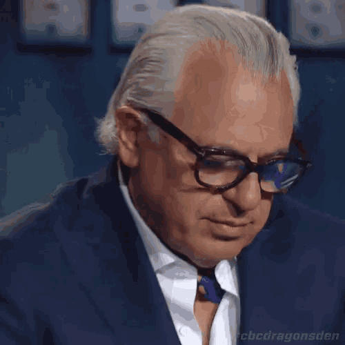 a close up of a man wearing glasses and a suit with the hashtag #cbcdragonsden
