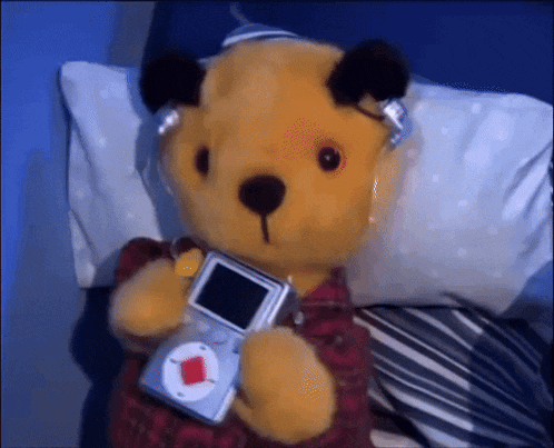 a teddy bear is wearing headphones and holding a small device