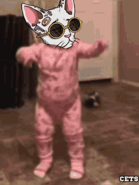 a baby wearing pink pajamas and sunglasses with a cat face on it