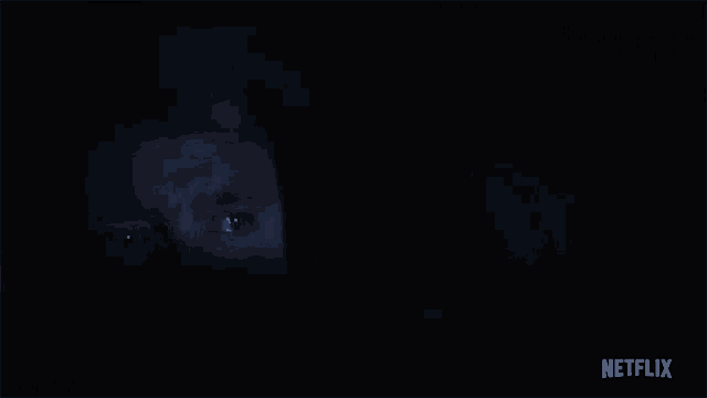 a man is laying on his back in the dark with his eyes closed and a netflix logo in the corner .