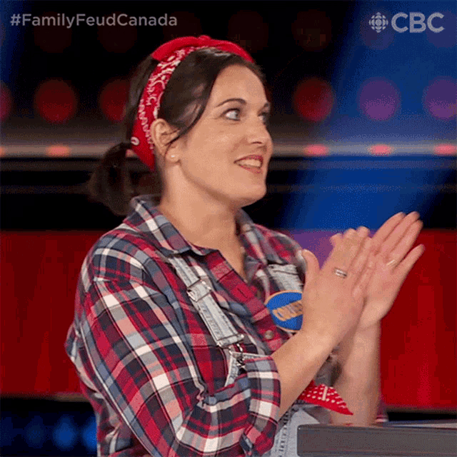 a woman wearing a plaid shirt and a red bandana is clapping her hands in front of a cbs logo