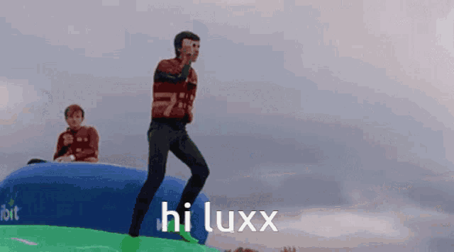 a man is jumping on a green and blue inflatable with the words hi luxx written on it