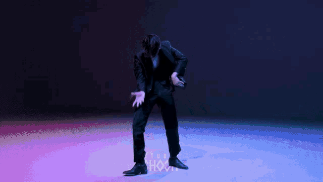 a man in a suit is dancing in front of a sign that says ' shock ' on it