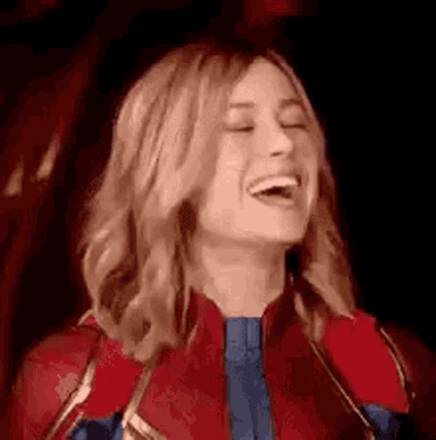 a woman in a superhero costume is laughing with her mouth open .