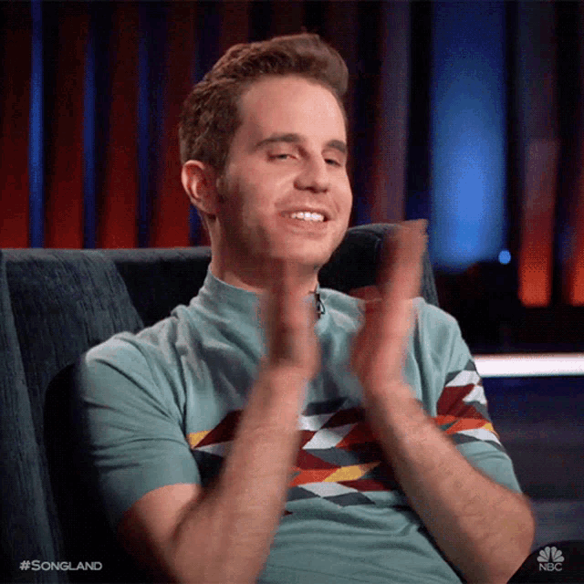 a man is clapping his hands while sitting in a chair .