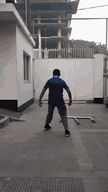 a man in a blue shirt is standing in front of a white gate