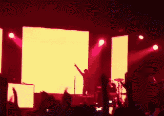a group of people standing in front of a stage with red lights behind them .