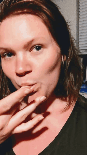 a close up of a woman 's face with her finger on her lips