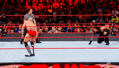 two wrestlers in a wrestling ring with a referee watching