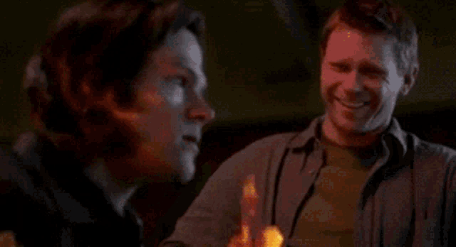 a man is standing in front of a fireplace that is on fire .