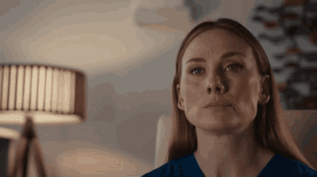 a woman in a blue shirt is sitting in a chair