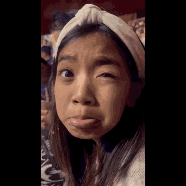 a girl wearing a headband making a funny face