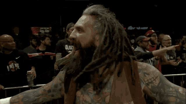 a man with dreadlocks and tattoos stands in front of a crowd wearing a shirt that says ' ohio state '