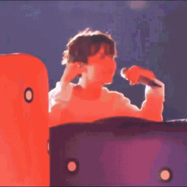 a person is singing into a microphone while sitting on a blue and red inflatable couch .