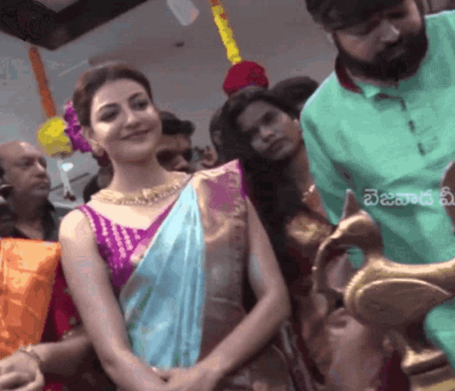 a woman in a blue and purple saree is surrounded by people